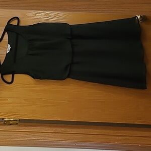 Black sleeveless dress cinched at the waist.